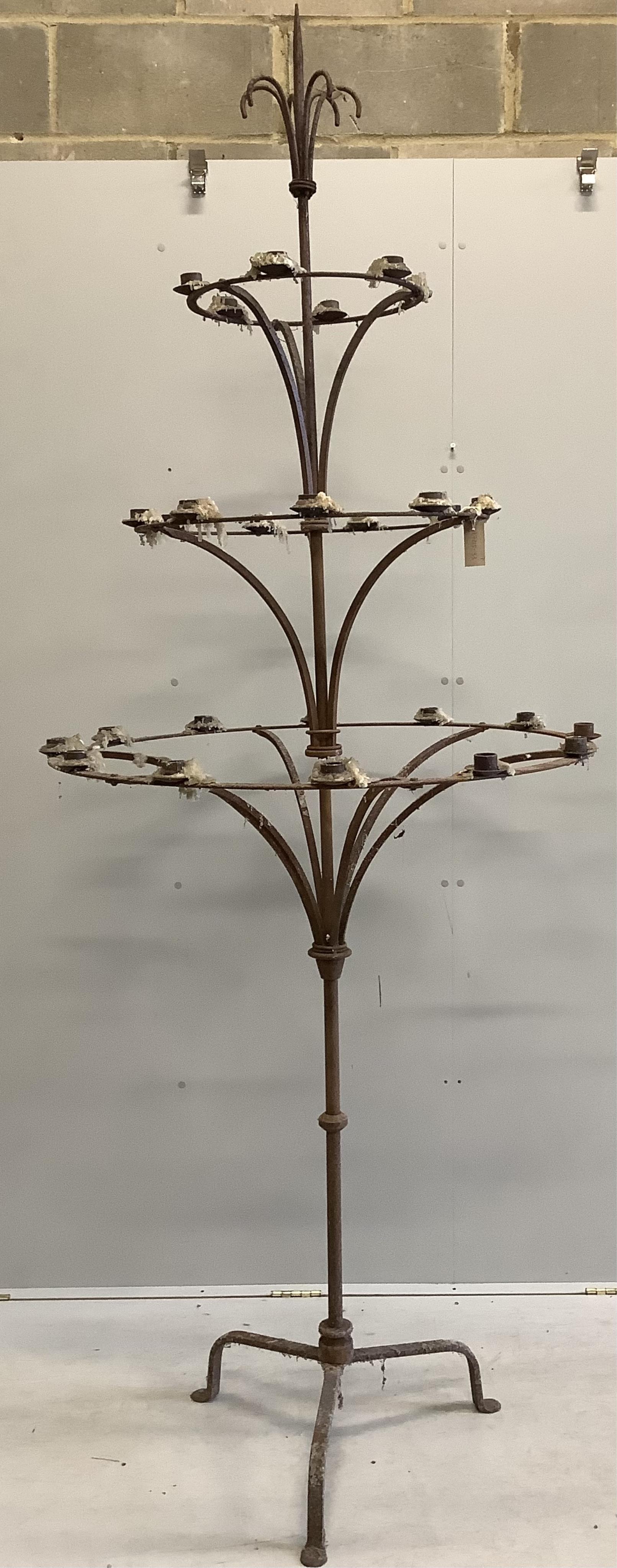 A pair of French wrought iron three tier candlestands, on tripod bases, diameter 95cm, height 254cm. Condition - fair although rusted